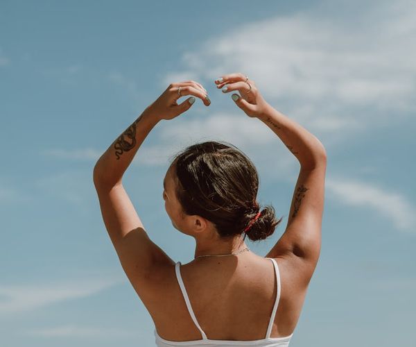 Woman stretching arms towards sky in bright living room